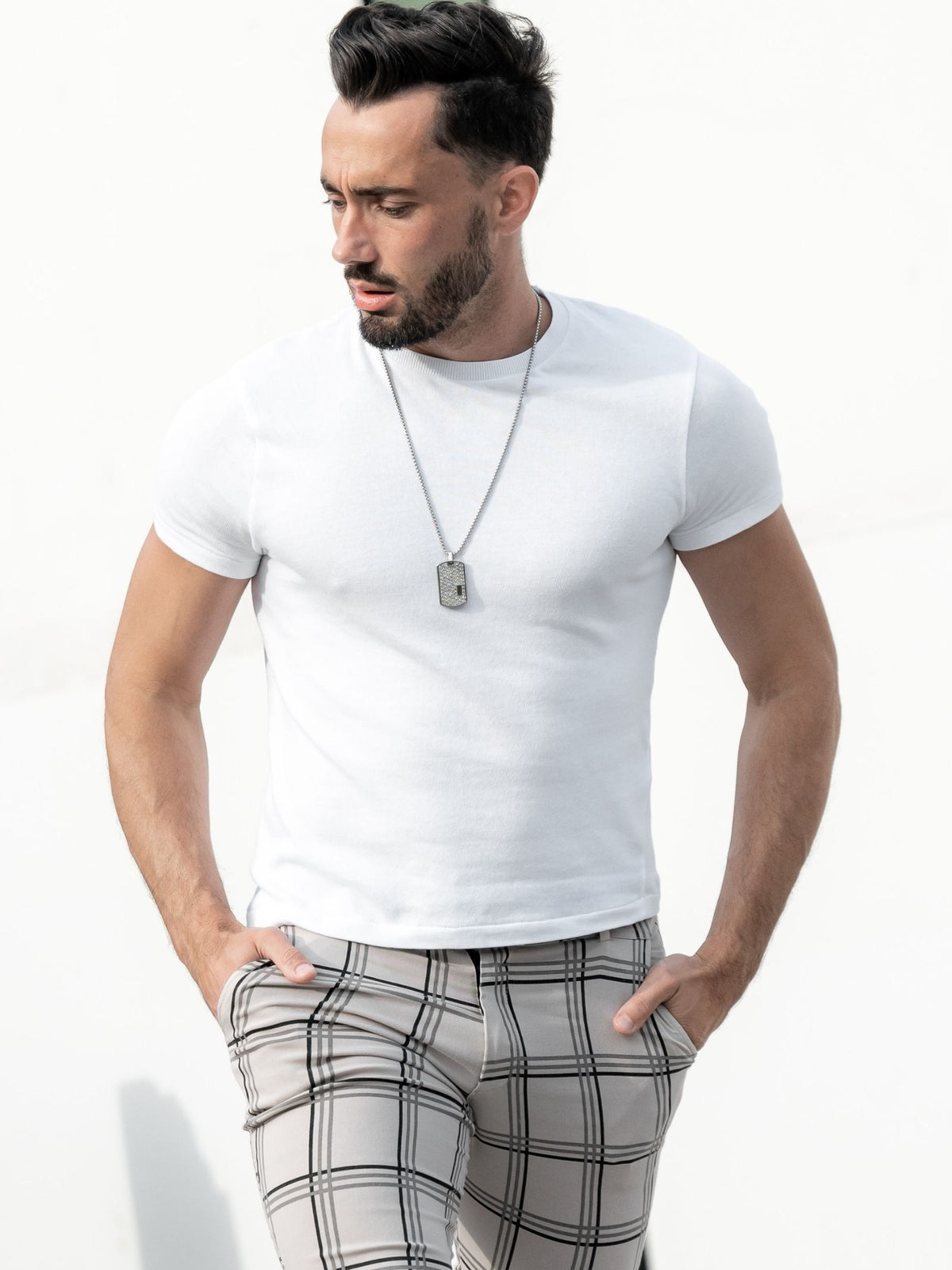 Silver-tone dog tag pendant necklace worn by model, chain and top bail visible