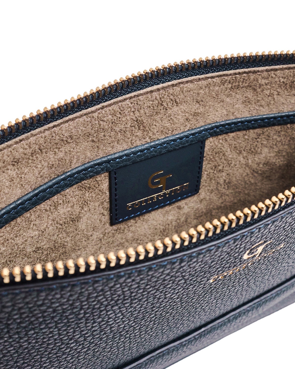Blue leather pouch interior view with tan lining, logo patch, gold-tone zipper edge.