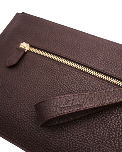Brown leather pouch corner showing gold zipper and embossed logo