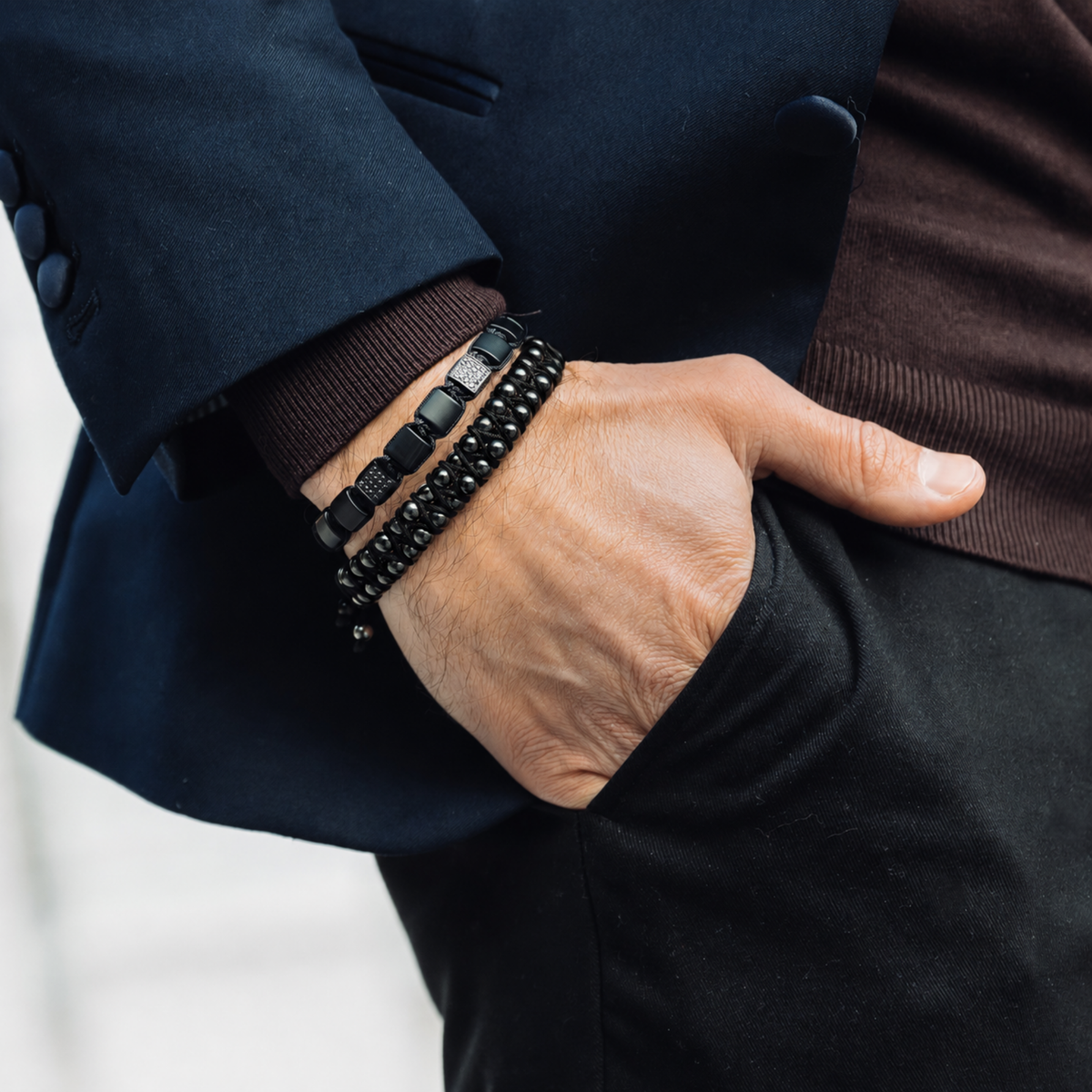 Stack of black bracelets on wrist: beaded style and woven cord style