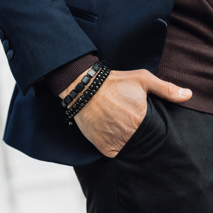 Stack of black bracelets on wrist: beaded style and woven cord style