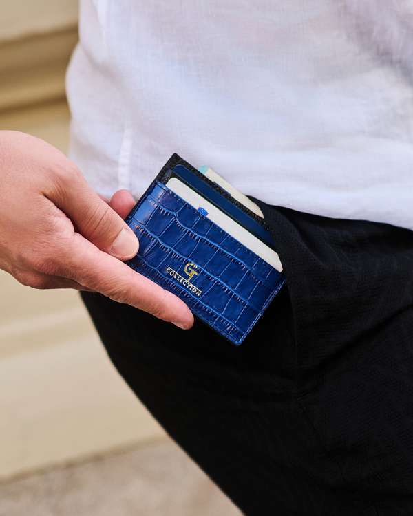 Blue croc-embossed card holder held in hand, showing card slot edge.