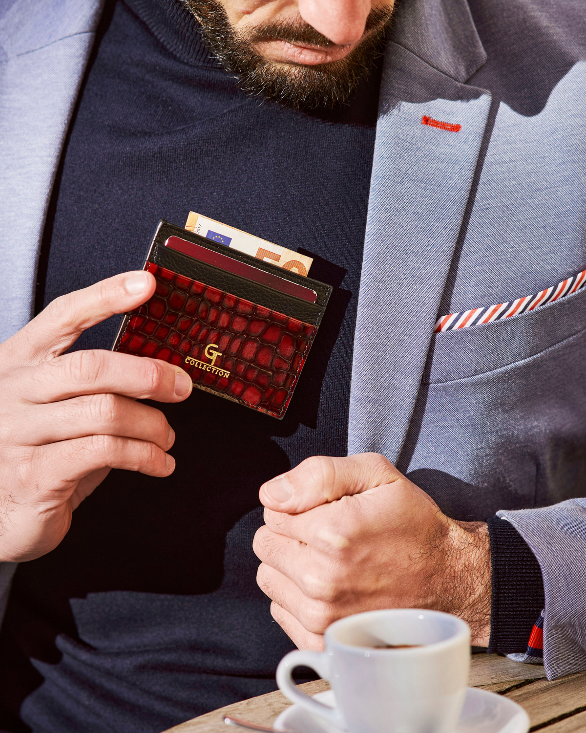 Red croc-embossed leather card holder in hand, showing gold logo and card slots.