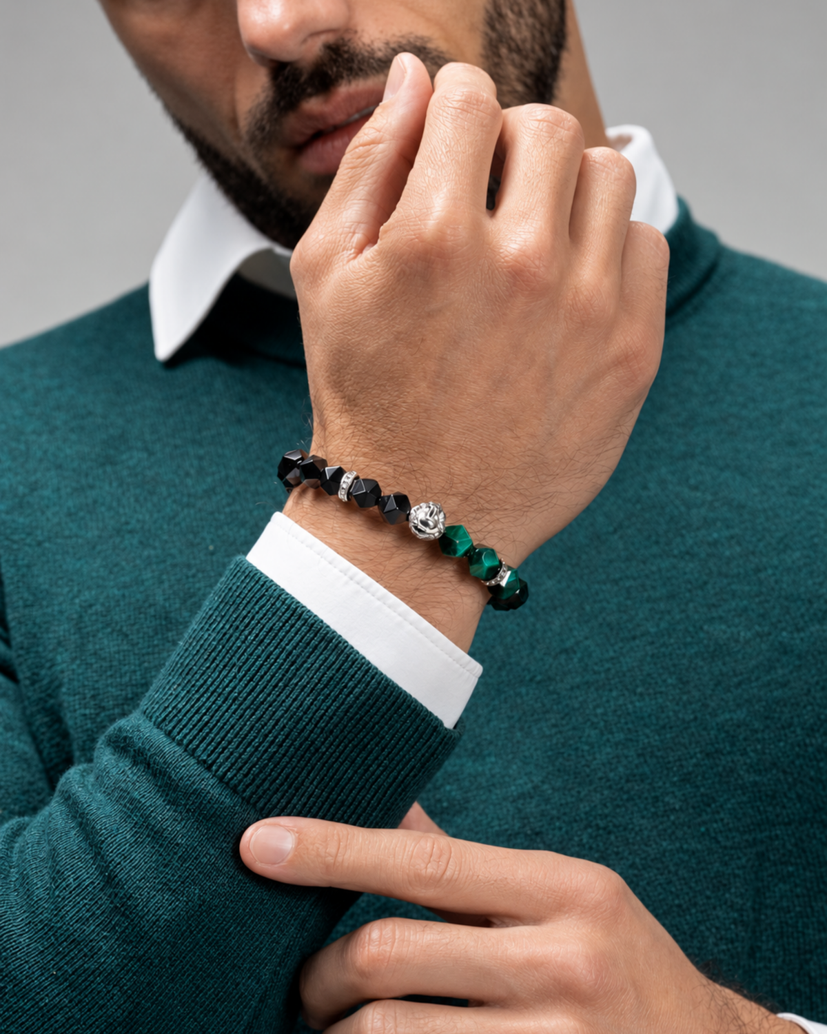 Lion charm bracelet worn on wrist, featuring black faceted beads and green stones.