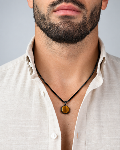 Black chain necklace with octagonal amber tiger-eye pendant worn at neckline