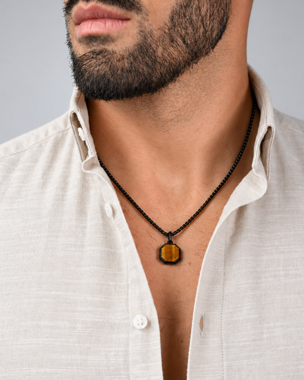 Black chain necklace with octagonal amber tiger-eye pendant worn under shirt collar