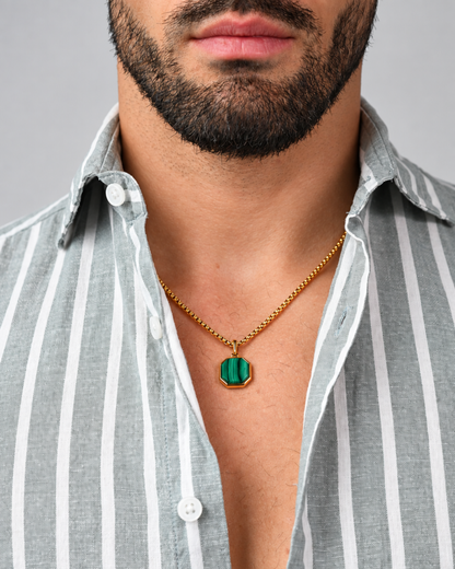 Gold chain necklace with green malachite octagonal pendant, worn with striped shirt