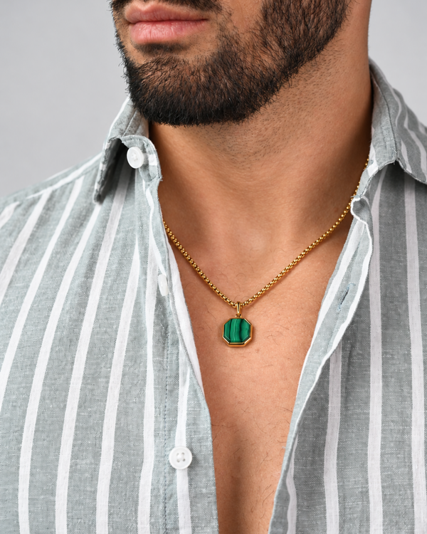 Gold chain necklace with octagonal green malachite pendant, worn at neckline