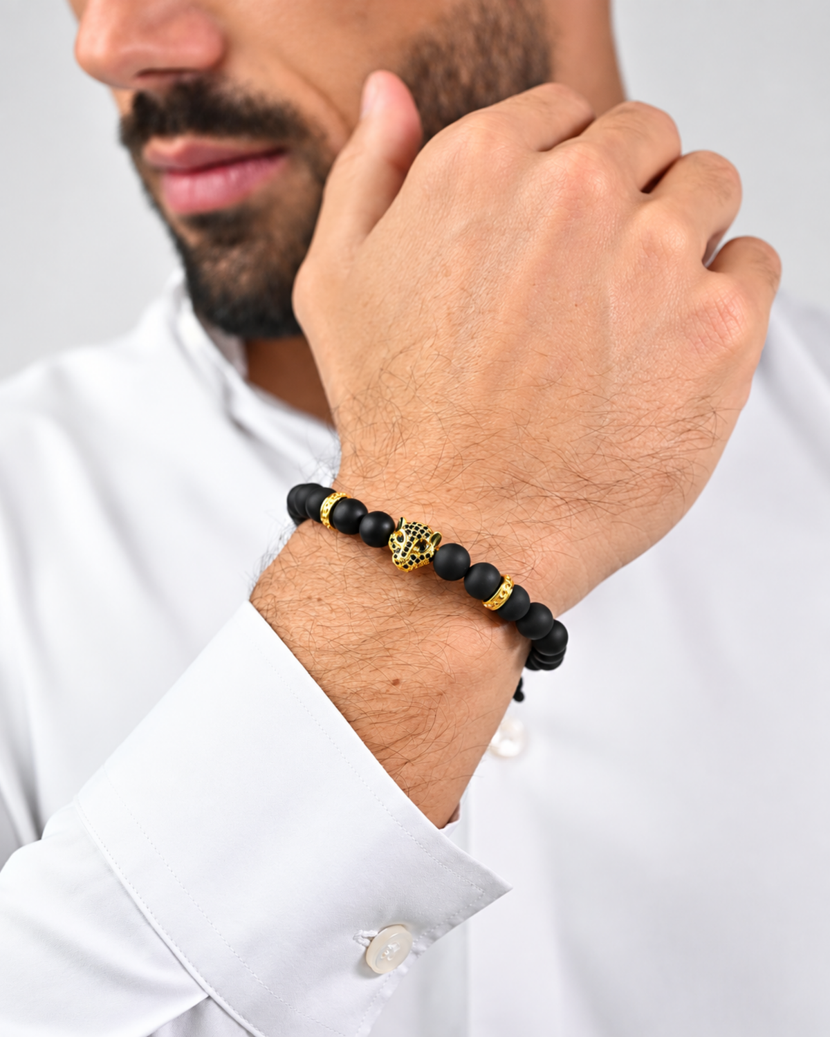 Black bead bracelet with gold leopard charm worn on wrist