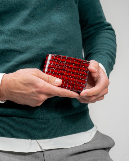 Red croc-embossed leather wallet held in hands, closed with card pocket detail.